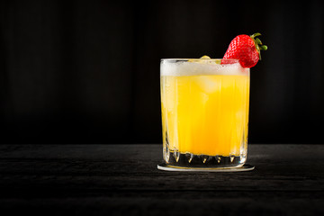 vintage style orange cocktail with strawberry on black background