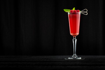 raspberry cocktail on black wooden bar with black background