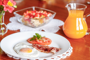 fried eggs, bacon, tomato, fruit salad and orange juice