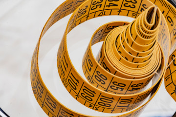 Yellow dressmaker's tape measure for clothing and its derivatives