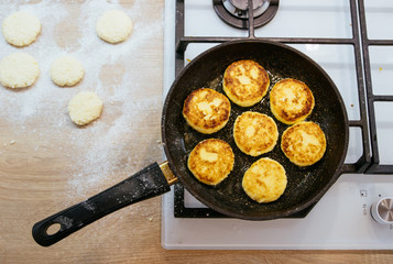Cheesecakes, curd cheese pancakes in frying pan on white background, top view