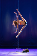 Fototapeta na wymiar girl athlete gymnast shows an acrobatic performance on a pylon