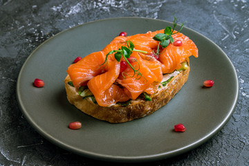 Bruschetta with salmon and cheese on black plate