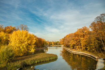 Autumn landscape. Bright golden colors of autumn against the blue sky are reflected in the water of a beautiful full-flowing river.