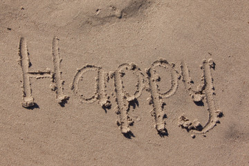 the word happy written in beach sand