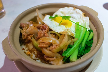 Rice with meat and fried egg and green onions in a pot