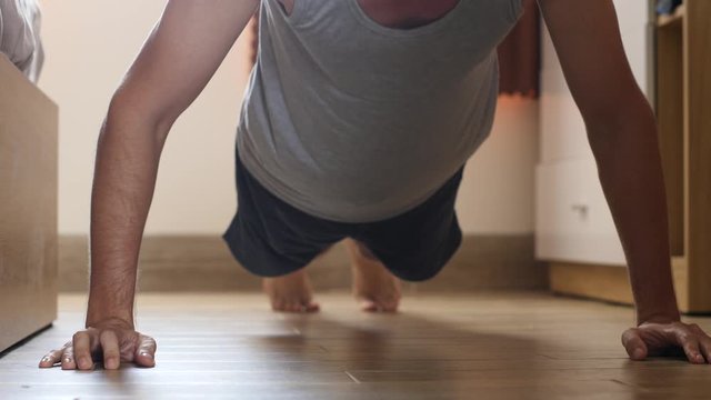 Muscular young man doing push up exercise on the floor at home.