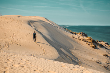 Fototapeta na wymiar A adventure travel man walking in wide endless beach dunes at the danish coastline in summer