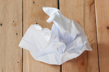 Crumpled paper ball on wooden surface