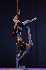 Fototapeta na wymiar young girls athlete gymnast shows an acrobatic performance on a pylon.
