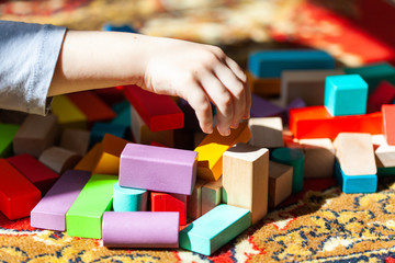 Playing colorful wooden cubes on carpet, sun