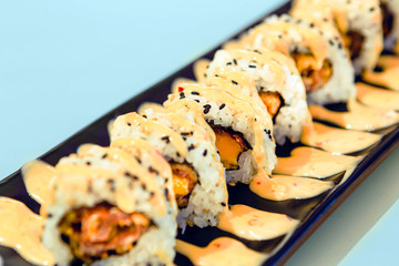 Delicious pieces of sushi on a plate with sauce with blue background