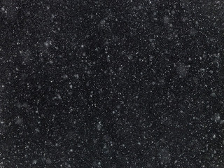Texture of flakes of falling snow on a dark background.