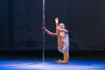 young girl athlete gymnast shows an acrobatic performance on a pylon