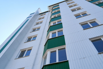 facade of a new multi-storey building with white and green metal siding, many Windows
