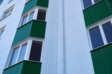 Obraz premium facade of a new multi-storey building with white and green metal siding, many Windows
