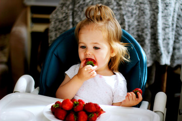 little girl eating strawberries at home
