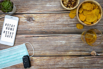 Smart phone screen with text hashtag #STAY HOME and #STAY SAFE. with mask, snacks and beverages. stay home stop virus concept.