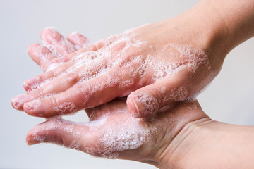Hygiene and protection of hands from viruses (coronavirus) and bacteria using soap. Women's hands with foamed soap close-up on a white background. The process of properly washing hands with soap.