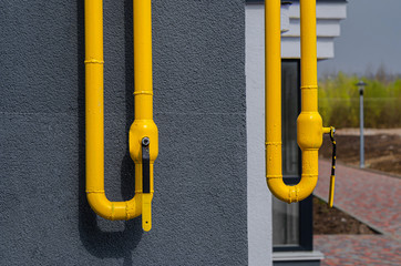 Yellow gas pipe with a vent on the facade of a multi-storey building. Natural gas for domestic...