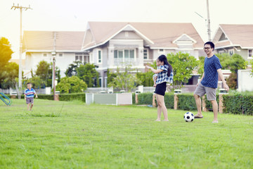 Fototapeta na wymiar Portrait of Asian family playing football together in garden
