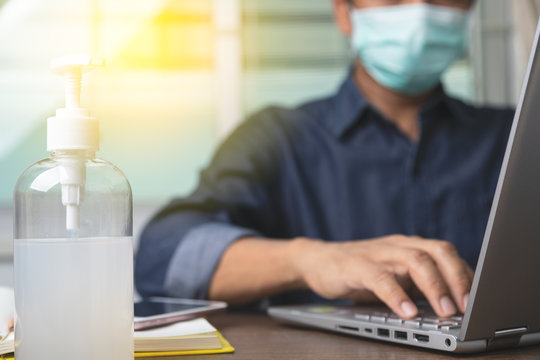 Alcohol gel with male employee wearing a health mask Preventing corona virus infection covid-19 in back, concept of working from home and social distancing.