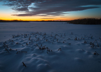 A vibrant winter twilight over a frozen wetland.