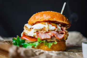Hamburger with egg beef and vegetables on a grey ceramic plate.