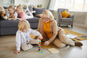 Grandmother playing with colored blocks together with her grandson on the floor in the living room
