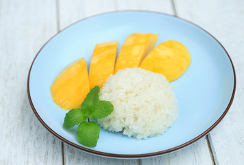 Sweet mixed coconut milk with sticky rice and yellow mango fruit on dish serving. Thai dessert for eating in daily life
