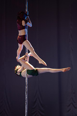 Naklejka na ściany i meble The duo of a girl athlete gymnasts show a pair acrobatic performance on the pylon.