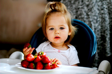 little girl eating strawberries at home