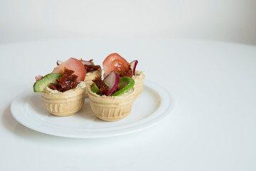  Four tartlets stuffed in a plate are on the table.