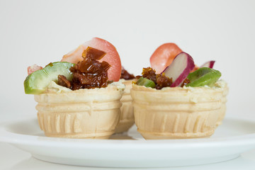 Four tartlets with vegetable filling close to lie on a plate.