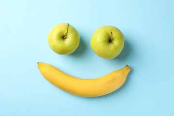 Smiley face made of bananas and apples on blue background