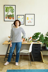 Female artist working from home stading next to her workplace and smiling. Freelance illustrator...