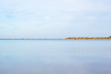 Línea del horizonte en el mar con espigón de rocas junto a la costa