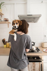 young woman cooks in the kitchen with a dog