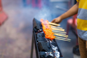 Street food seller in Asia fries chicken mini barbecue on the grill