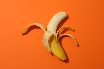 Opened banana on orange background. Fresh fruit