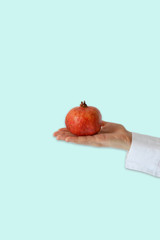 Hand holding a pomegranate isolated on blue background
