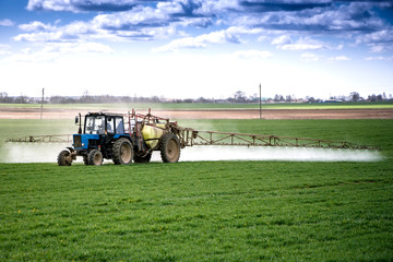 A tractor sprays a field with growth supplements and will destroy plant diseases. Agriculture....