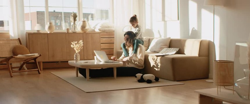 Mother working from home, having a phone call, while her daughter distracts her and drawing attention. Shot on RED Dragon
