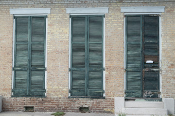 Three shuttered windows on brick wall