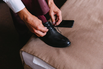 An elegant bride knits shoelaces on classic shoes