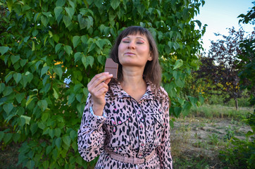 Delighted girl eating a chocolate bar closing her eyes with pleasure on the edge of enjoyment 