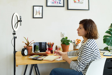 Female artist filming illustration process at home. Creative blogger working from home making...