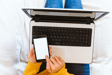young woman working on laptop at home, sitting on the couch, wearing protective mask. Stay home concept during coronavirus covid-2019