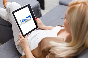 Joyful woman enjoying online shopping in bed