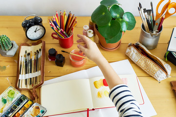 Close-up image of artist drawing in a sketchbook. Female designer working from home. Creative cozy...